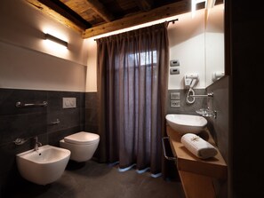 A modern bathroom with a bidet, toilet, vanity with a sink, and a towel rack.