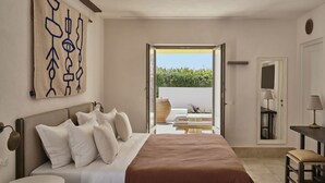 Une chambre avec un grand lit, une table de chevet, une commode, un miroir et une vue sur une terrasse extérieure aménagée avec des sièges et un grand vase.