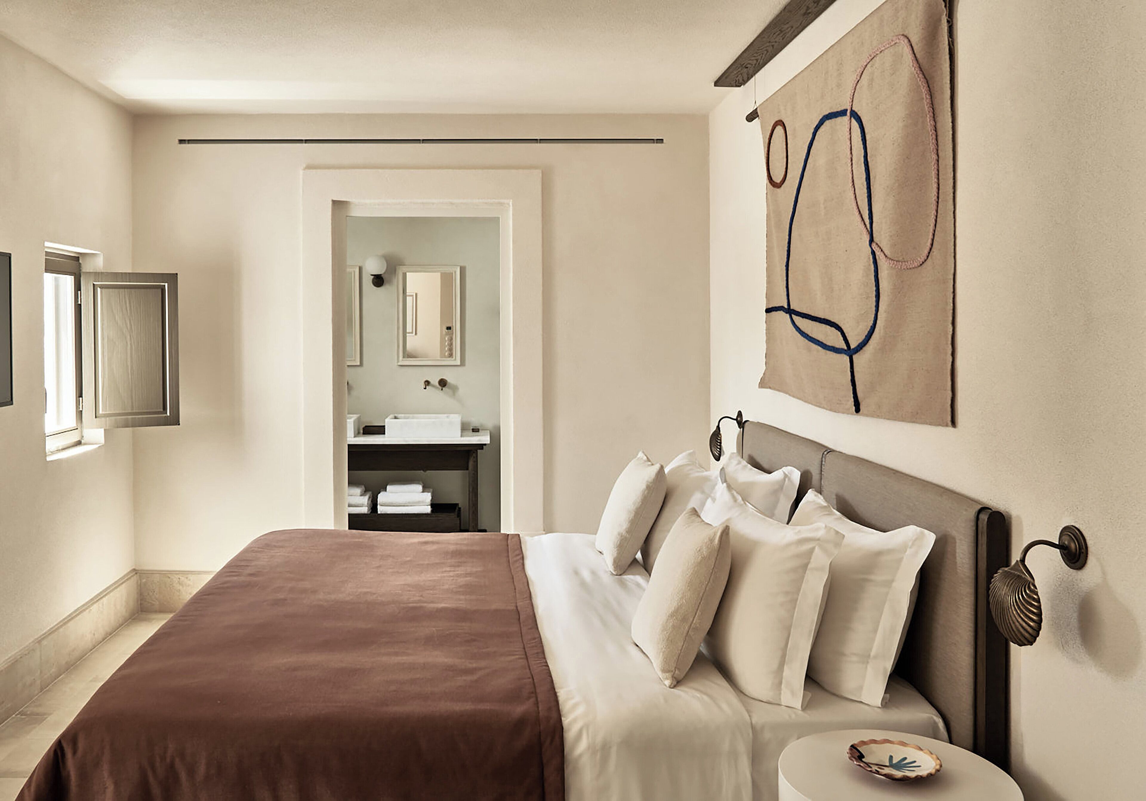 Une chambre d’hôtel avec un grand lit, une table de chevet, un miroir et une œuvre d’art accrochée au mur.