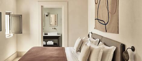 Une chambre d’hôtel avec un grand lit, une table de chevet, un miroir et une œuvre d’art accrochée au mur.