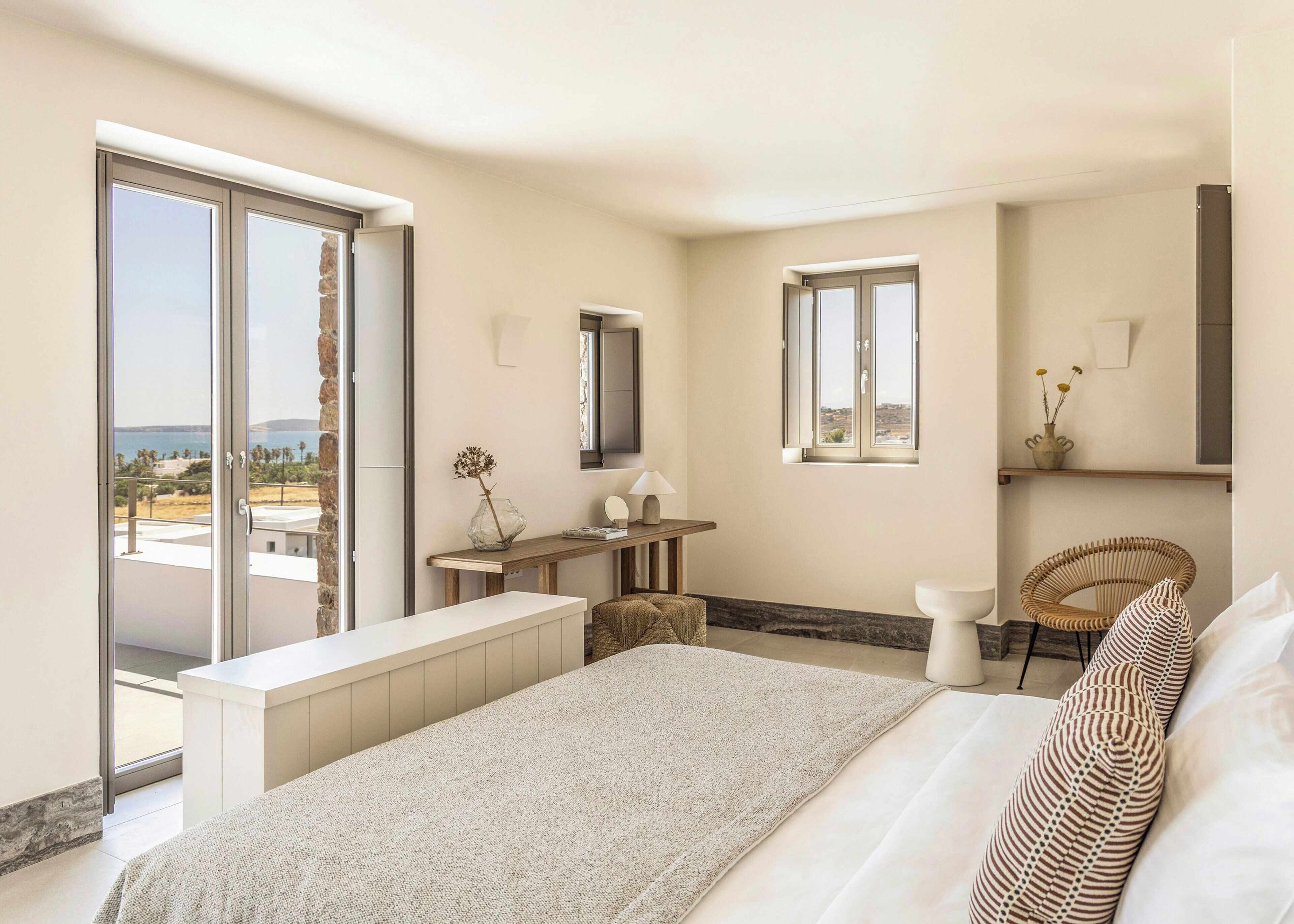 Un dormitorio con una cama grande, un escritorio, una silla, una mesita y una ventana con vistas.