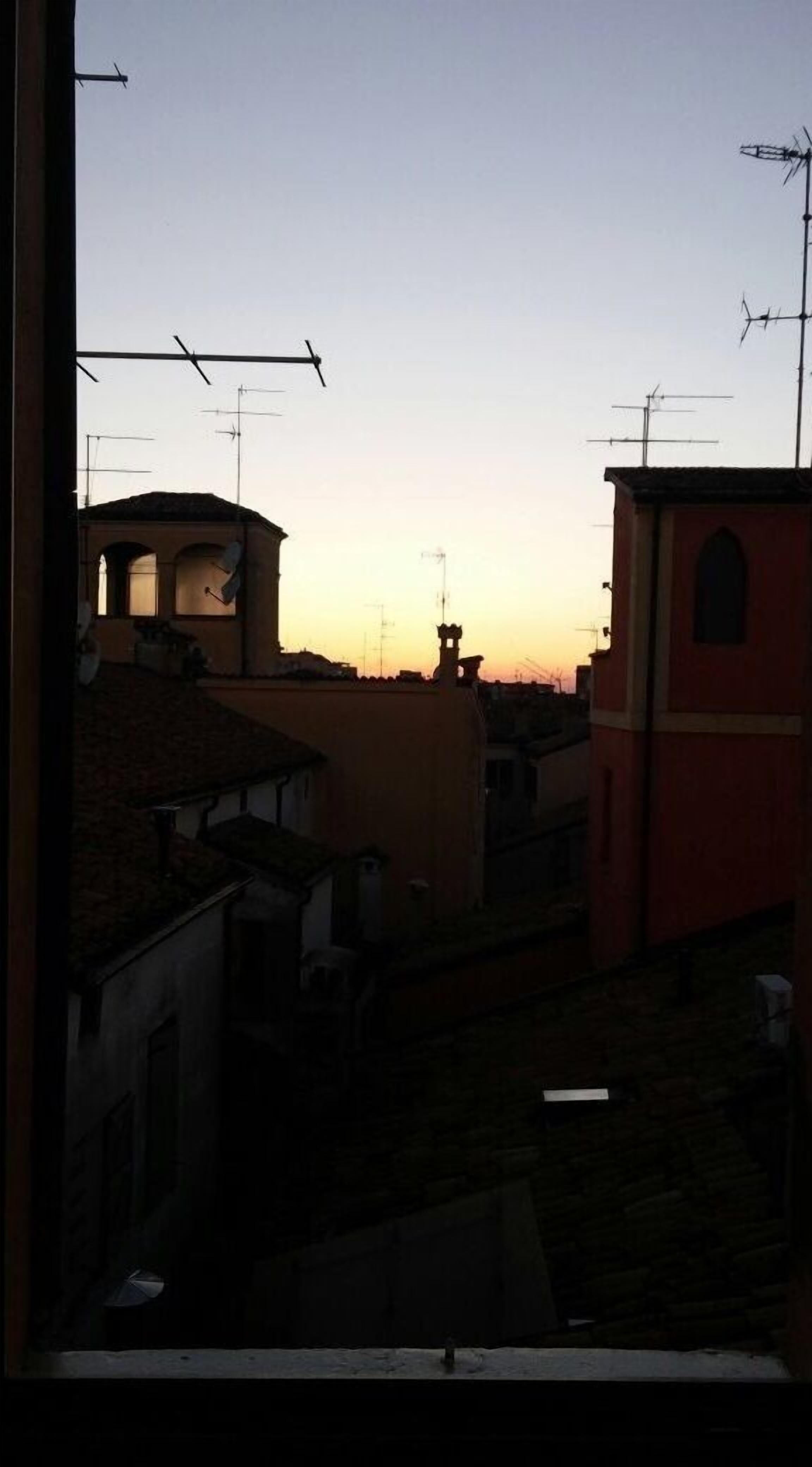 Paesaggio con edifici, antenne, cielo sereno e tramonto.
