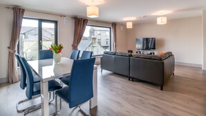 Un salon moderne comprenant un coin repas, un ensemble de canapés et un téléviseur.