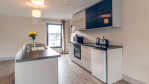 Une cuisine moderne dotée d’un îlot central, d’appareils électroménagers intégrés et offrant une vue sur l’extérieur.