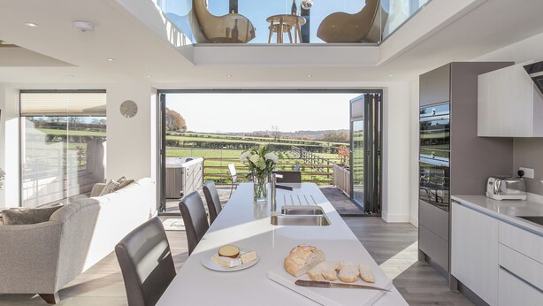 A modern kitchen with a dining area, large windows, and a view of the countryside. - The Lookout - UKC3846 (Ticknall, near Derby)