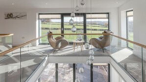 A spacious living area with a glass railing, modern furniture, and a view of the countryside. - The Lookout - UKC3846 (Ticknall, near Derby)