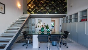 Une cuisine moderne avec une table à manger en verre, deux chaises, un escalier et un meuble à vin.
