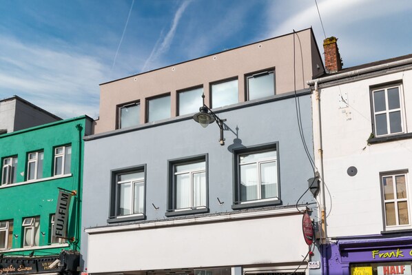 A multi-story building with a mix of architectural styles, including a green facade and a white upper section. - Central Park Apartment 2 (Killarney)