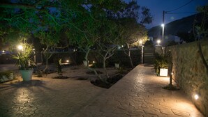 Um pátio com piso de pedra, plantas em vasos e uma escadaria que leva a um edifício.
