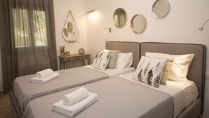Quarto de hotel com duas camas, uma mesa de cabeceira, um espelho e uma janela com cortinas.