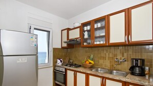 A kitchen with a refrigerator, stove, sink, and cabinets. - Apartment Topic near Beach (Podstrana)
