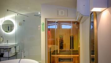 A modern bathroom with a freestanding bathtub, a glass-enclosed shower, and a wooden sauna.