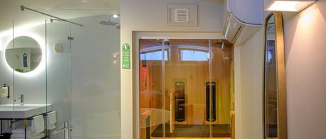 A modern bathroom with a freestanding bathtub, a glass-enclosed shower, and a wooden sauna.
