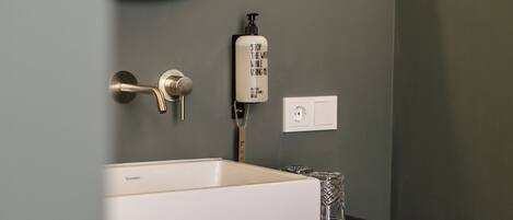A bathroom with a white sink, a black vanity, a mirror, and a towel rack.