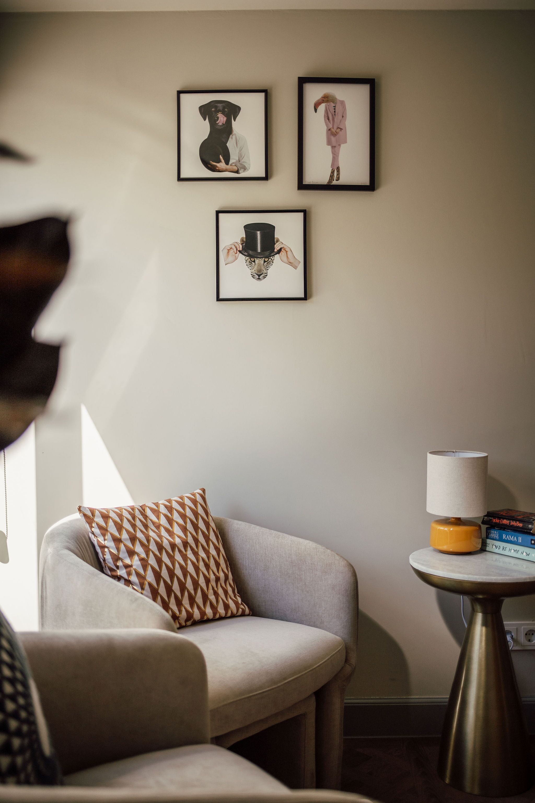 Ein Wohnzimmer mit einer Couch, einem kleinen Tisch mit Lampe und gerahmten Bildern an der Wand.