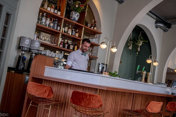 A bar area with a bartender, wooden shelves with bottles, and a modern bar counter. - FINCH Boutique Hotel (Deventer)
