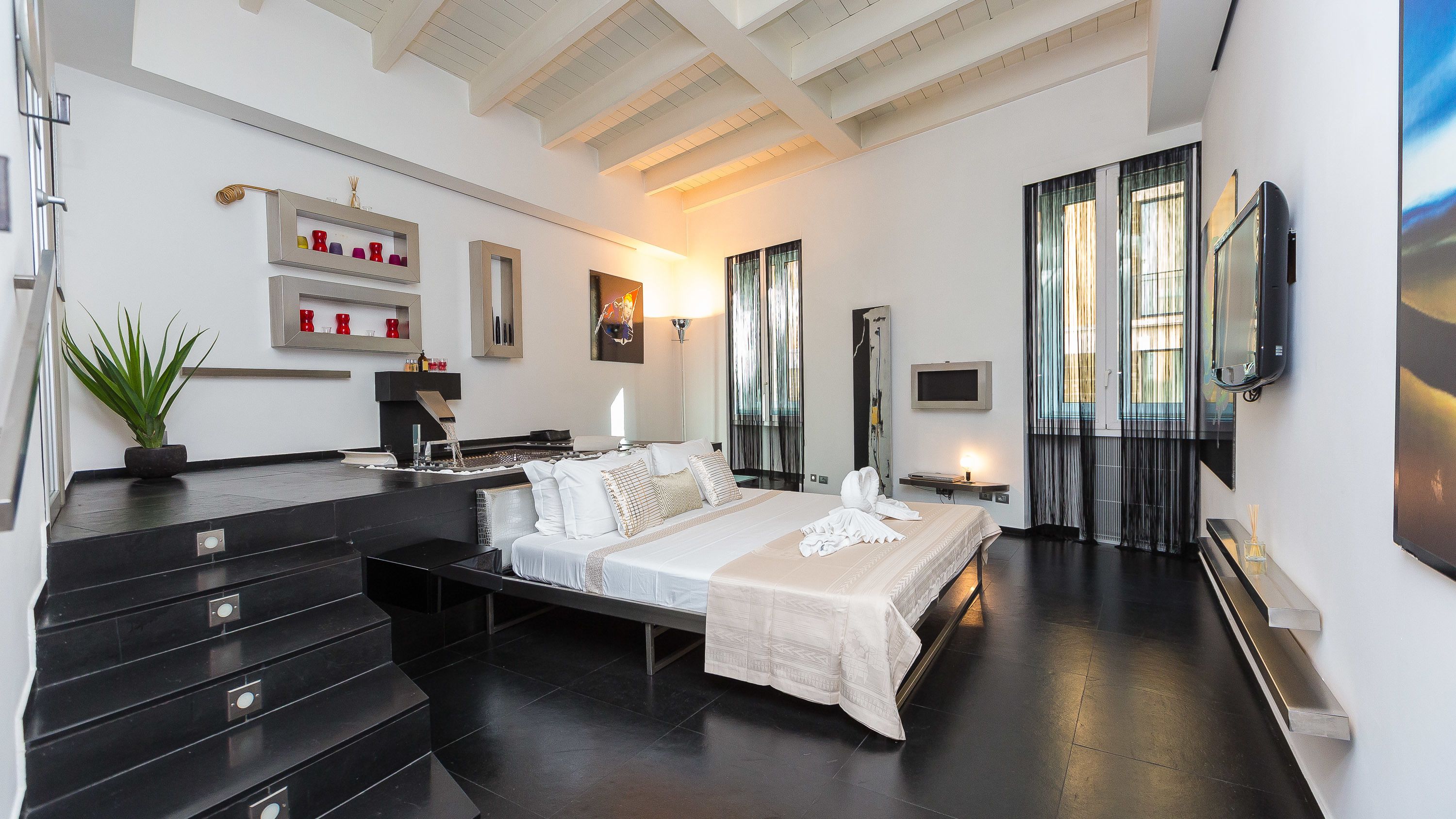 Una habitación de hotel moderna con una cama grande, una cafetera, un televisor y una escalera.