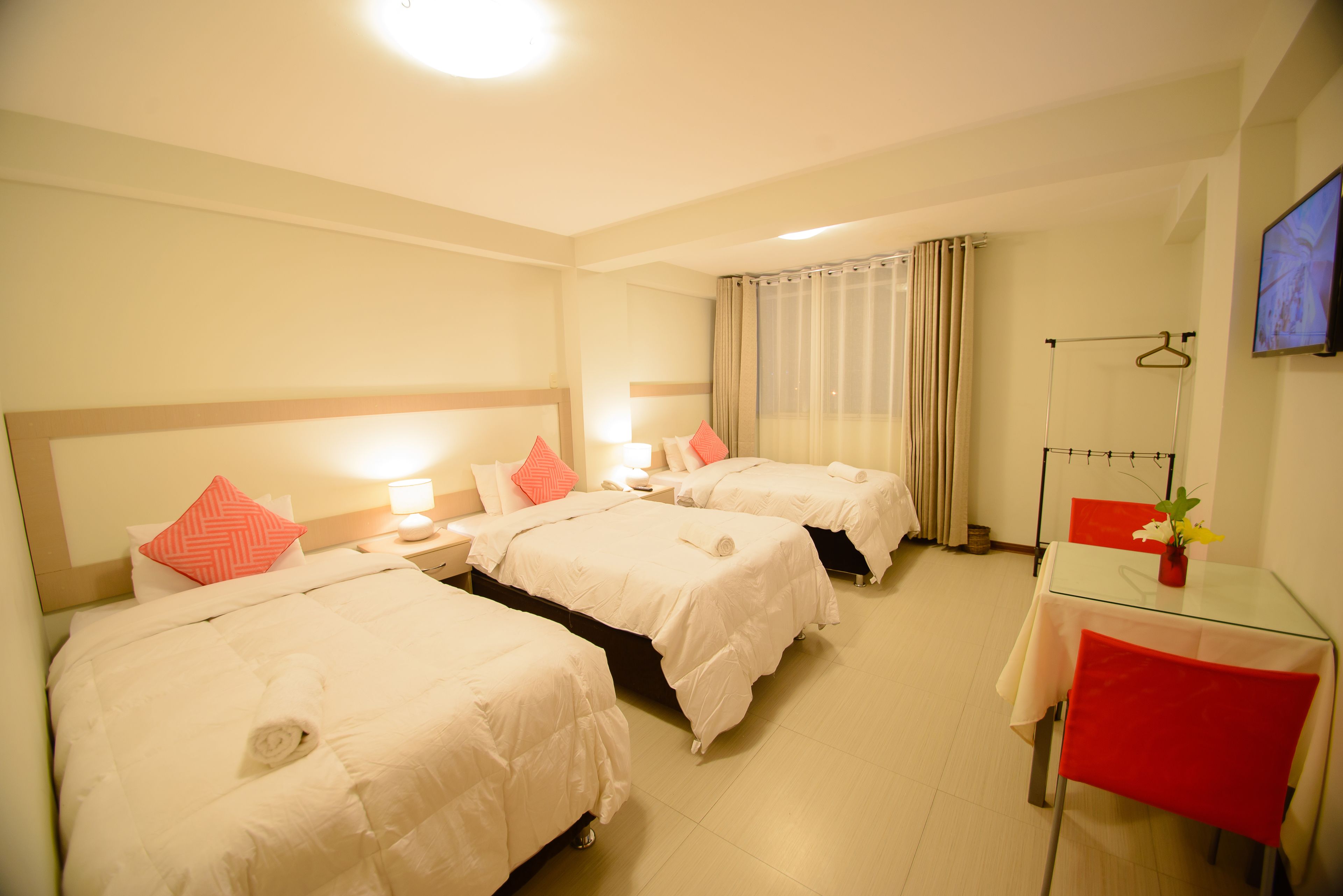 Ein Hotelzimmer mit zwei Betten, einem Glastisch und einem roten Sessel.