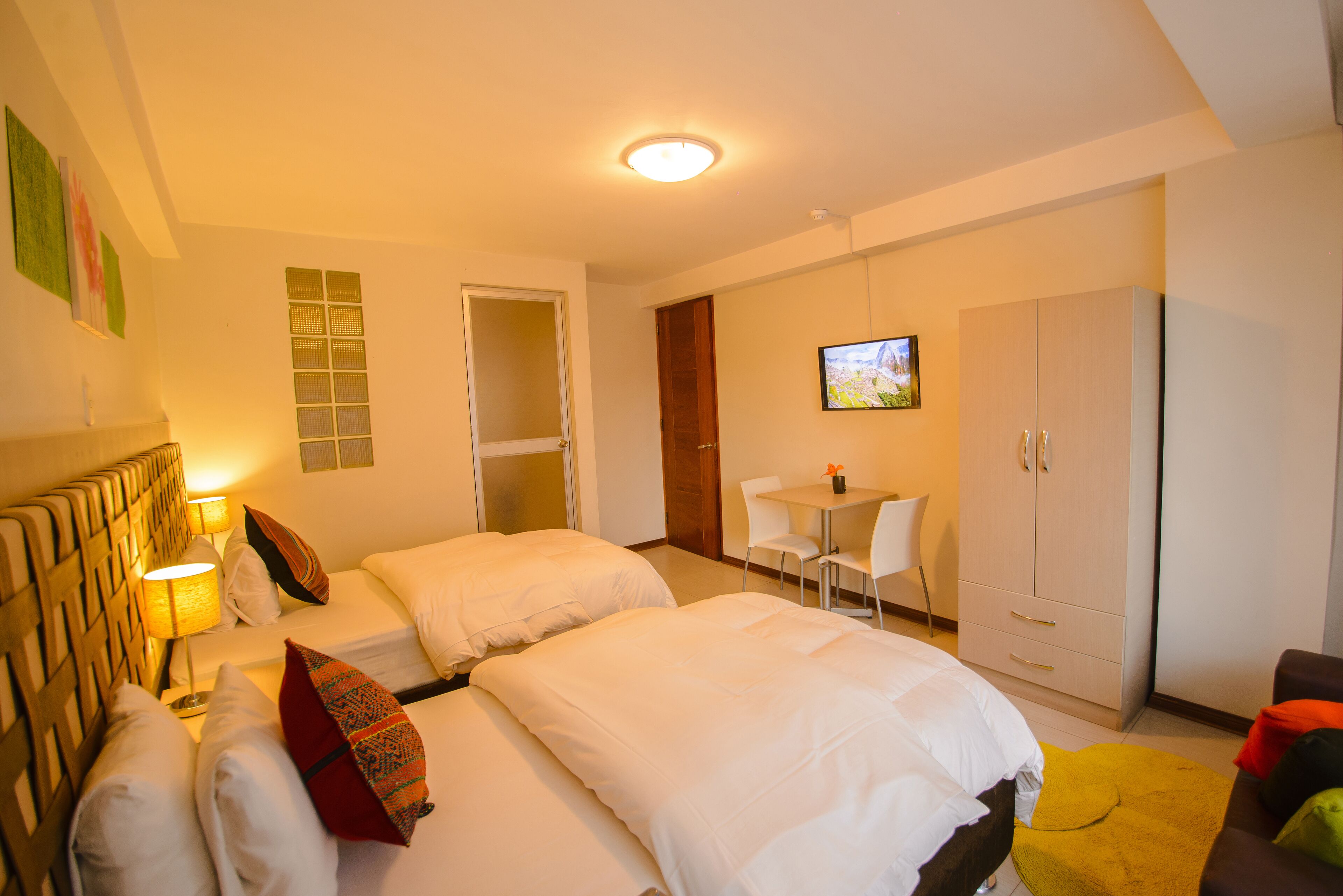 A hotel room with two beds, a desk, a TV, and a wardrobe.