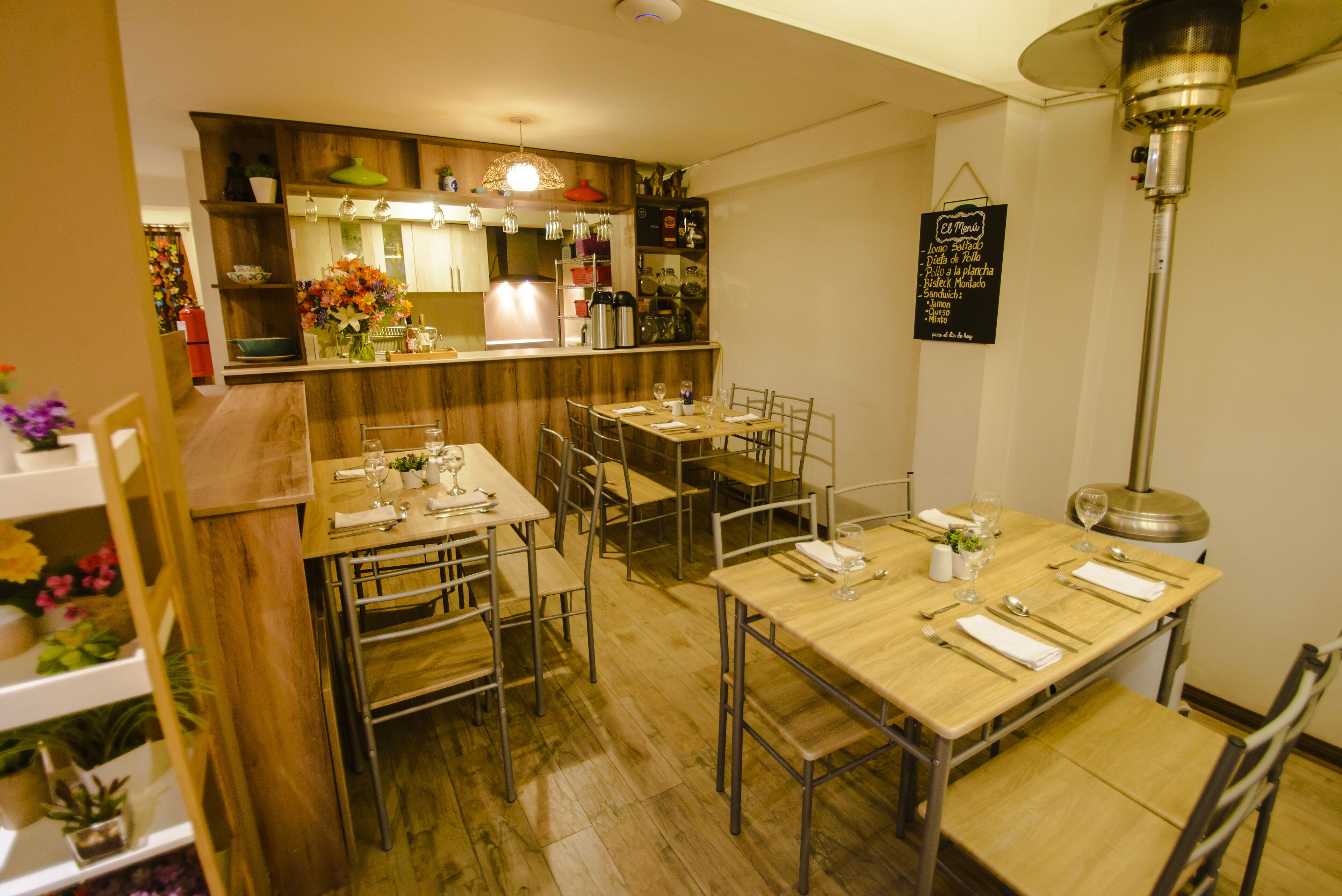 A restaurant with wooden tables and chairs, a bar area, and a menu hanging on the wall.