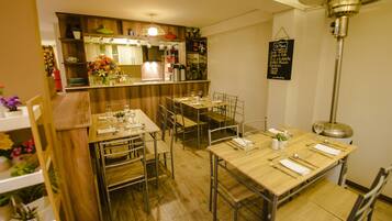 A restaurant with wooden tables and chairs, a bar area, and a menu hanging on the wall.
