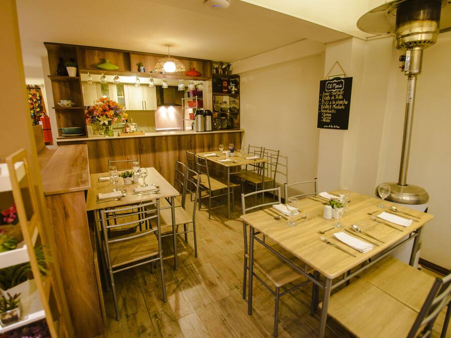 A restaurant with wooden tables and chairs, a bar area, and a menu hanging on the wall.