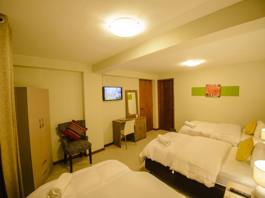 A hotel room with two beds, a desk, a chair, a wardrobe, and a television.