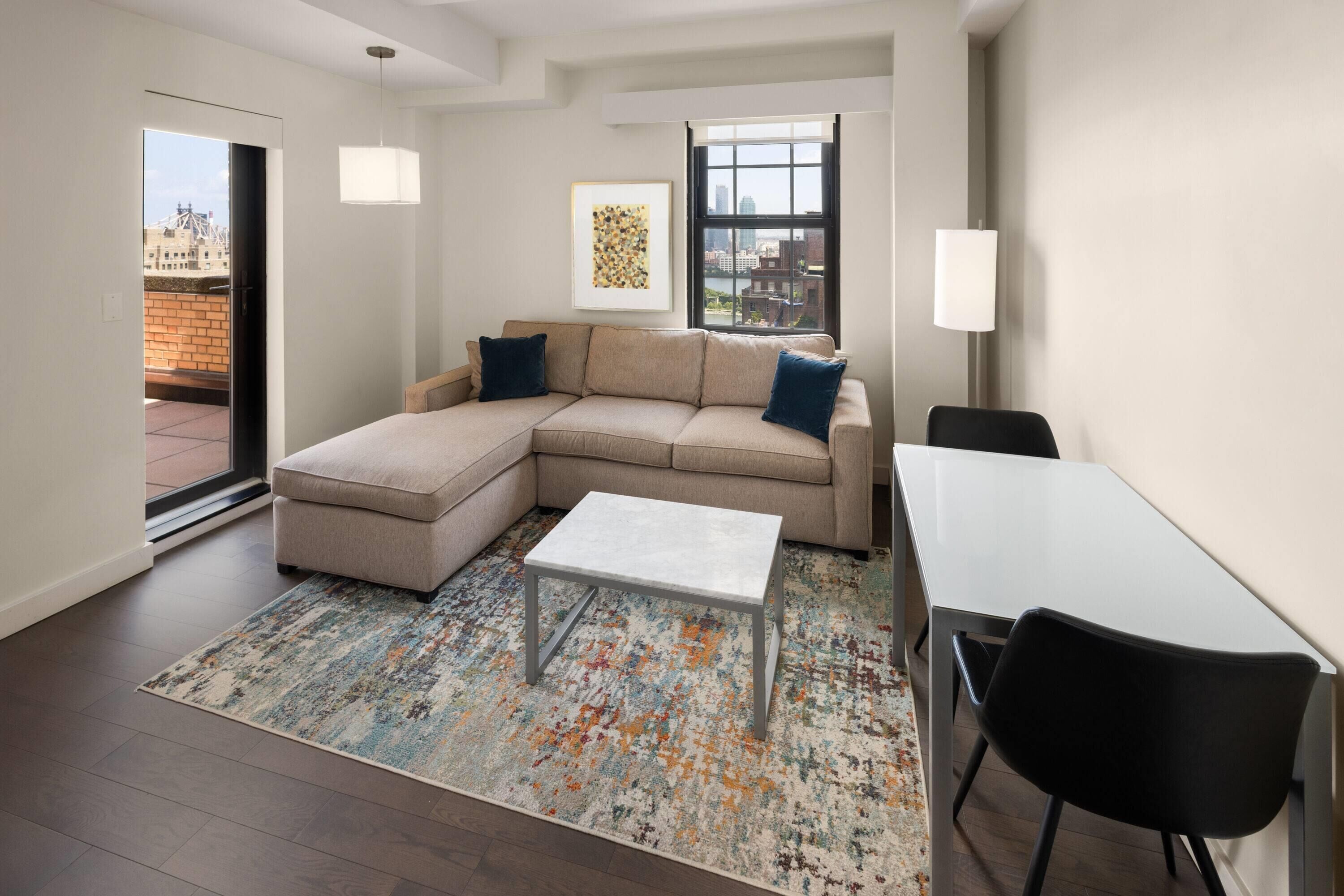 A modern living room with a sectional sofa, a small white table, and a dining area with a black chair.