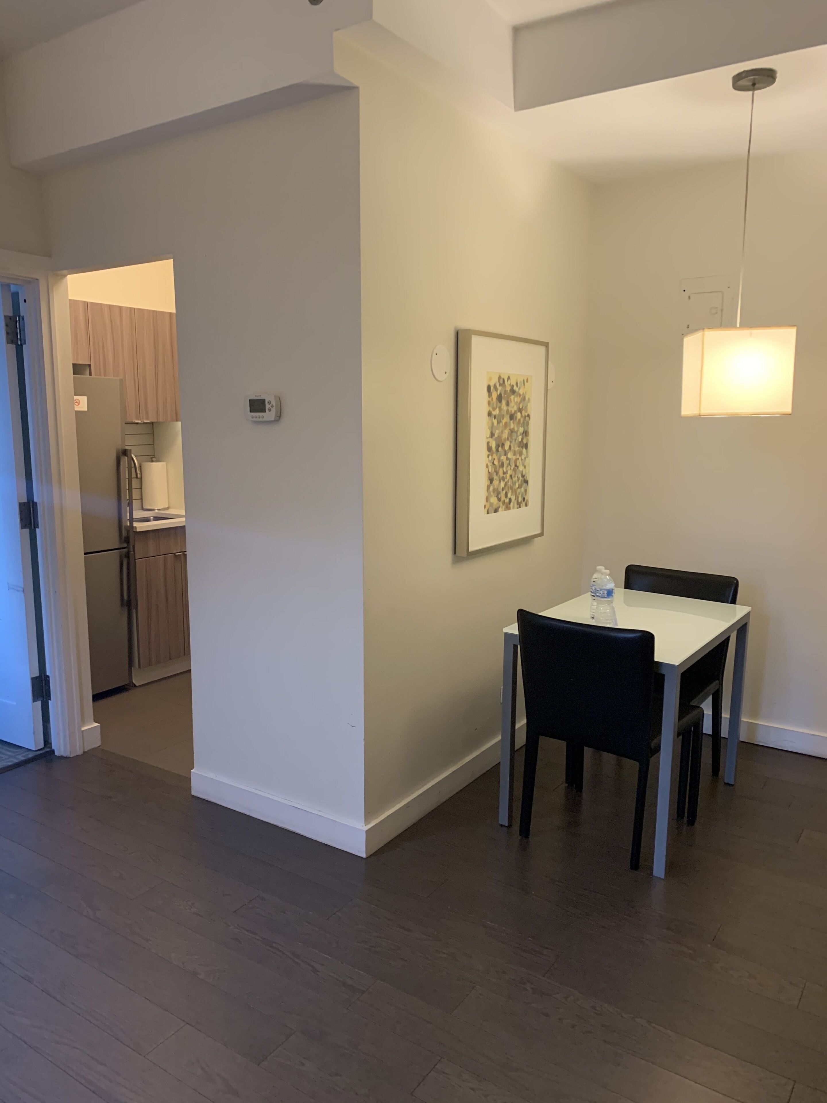 A modern apartment with a dining area, kitchen, and a hallway leading to another room.