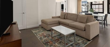 Una sala de estar moderna con un sofá modular, una mesa de centro y un televisor sobre un mueble de madera.