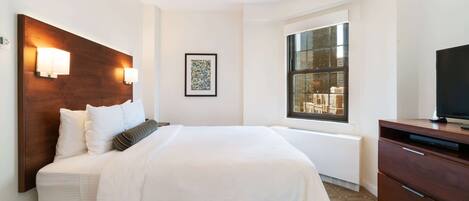 A modern hotel room with a large bed, bedside lamps, a window with a view, and a TV on a wooden cabinet.