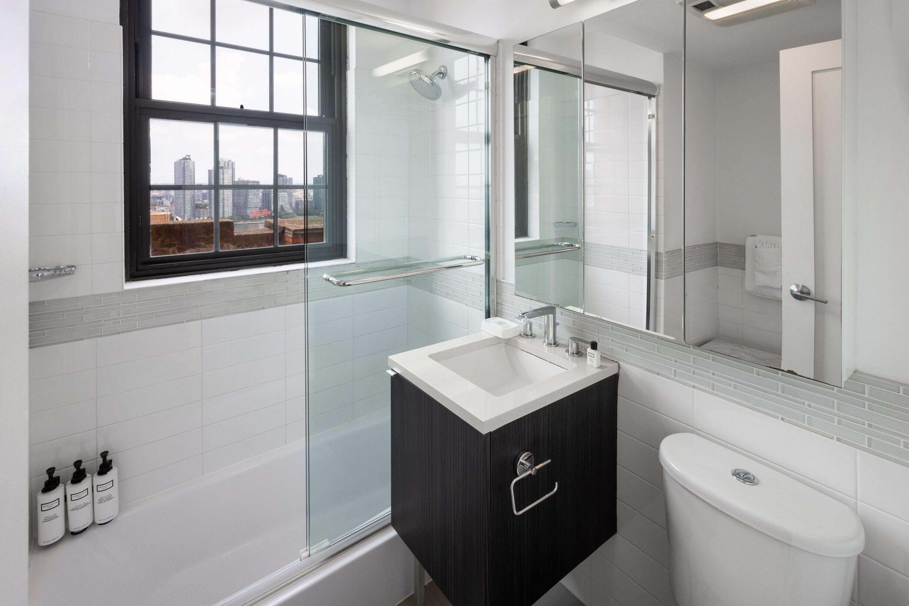 A modern bathroom with a glass-enclosed shower, a white sink, and a dark vanity.