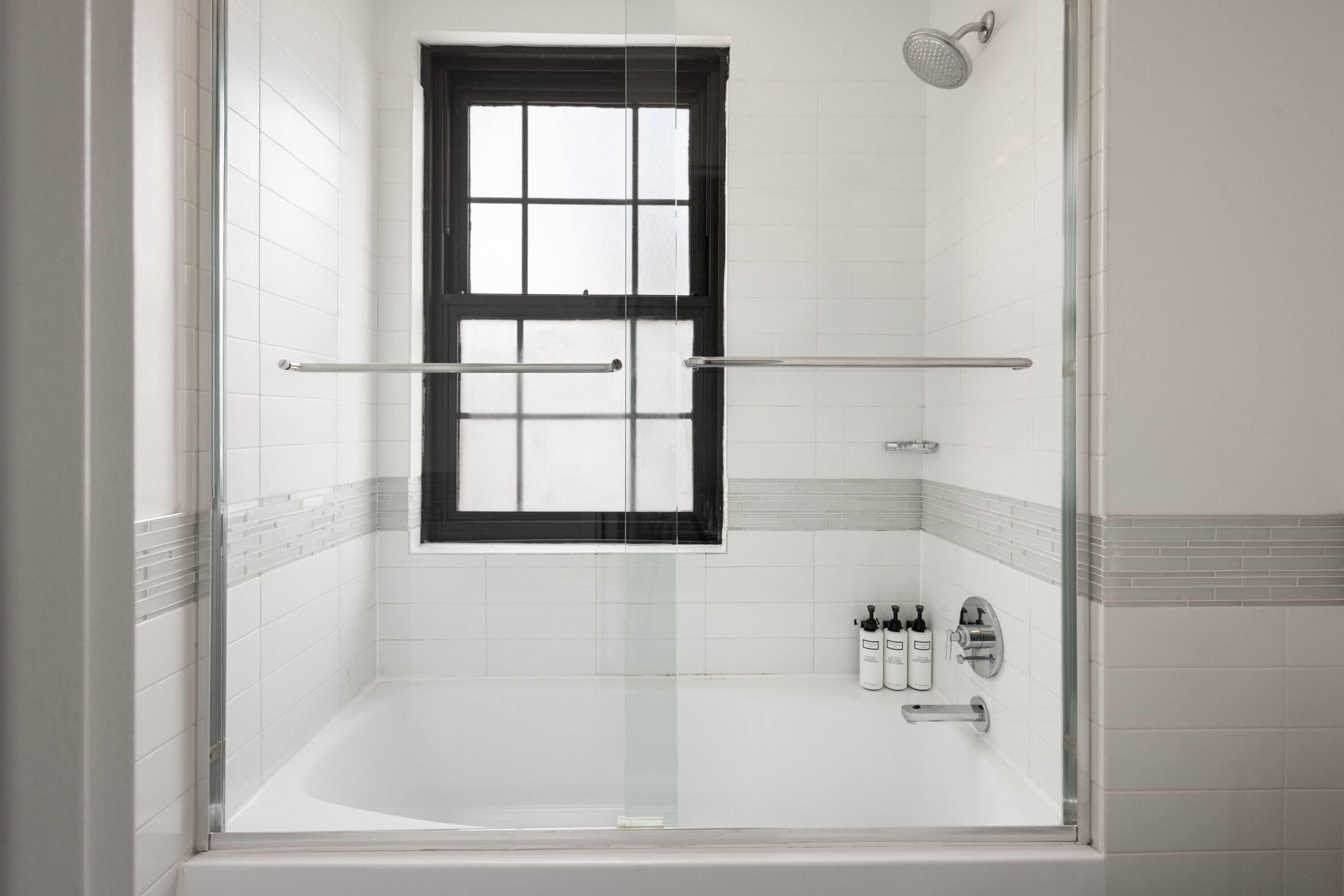 Un baño moderno con ducha acristalada, bañera y ventana.