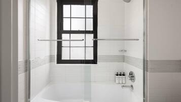 A modern bathroom with a glass-enclosed shower, a bathtub, and a window.