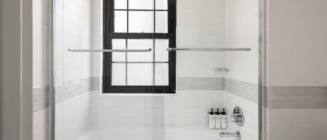 Un baño moderno con ducha acristalada, bañera y ventana.