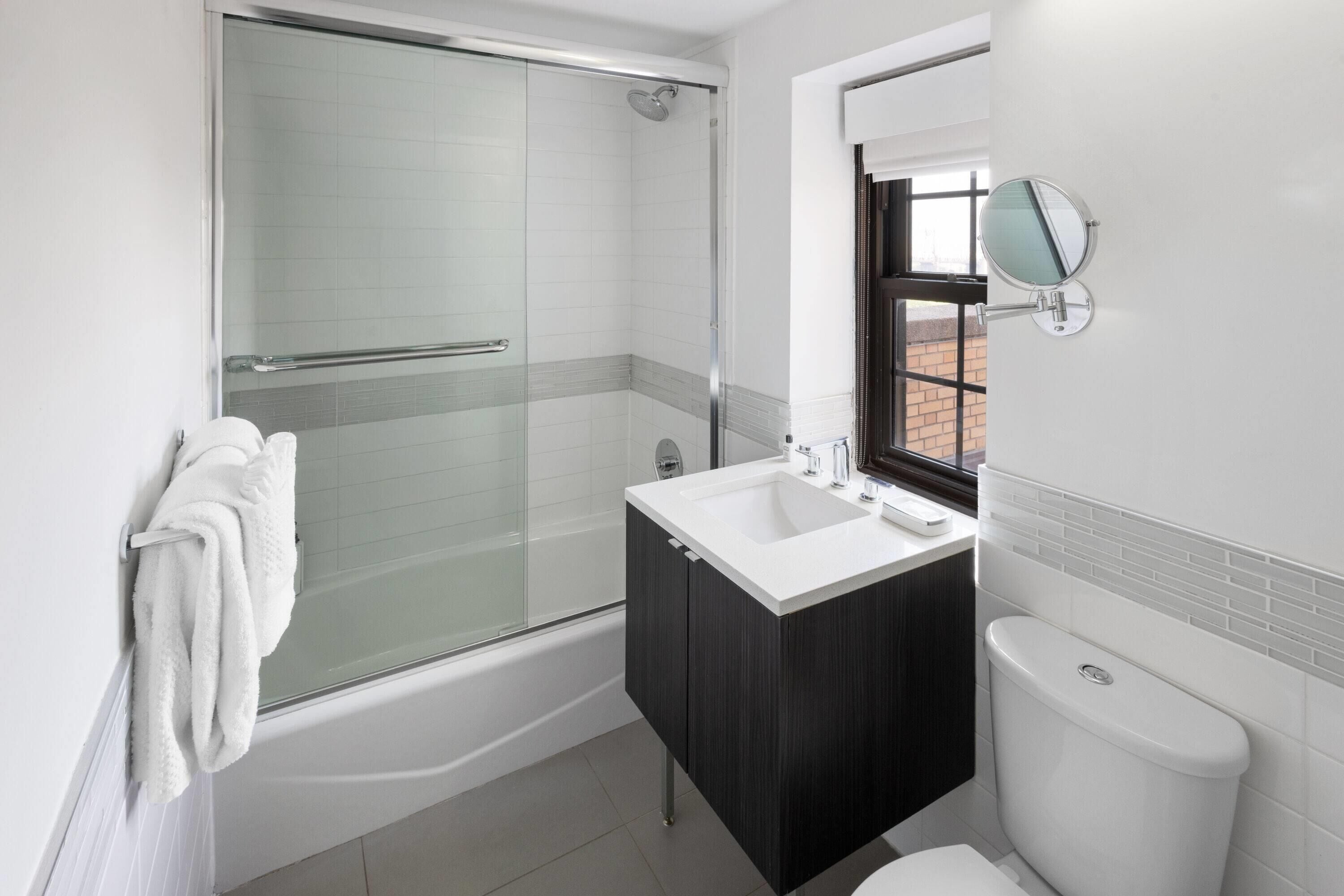 Une salle de bain moderne avec une douche à parois de verre, un lavabo blanc et un meuble en bois foncé.