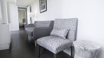 Un salon moderne avec un canapé gris, un fauteuil à motifs et une table d’appoint en marbre.