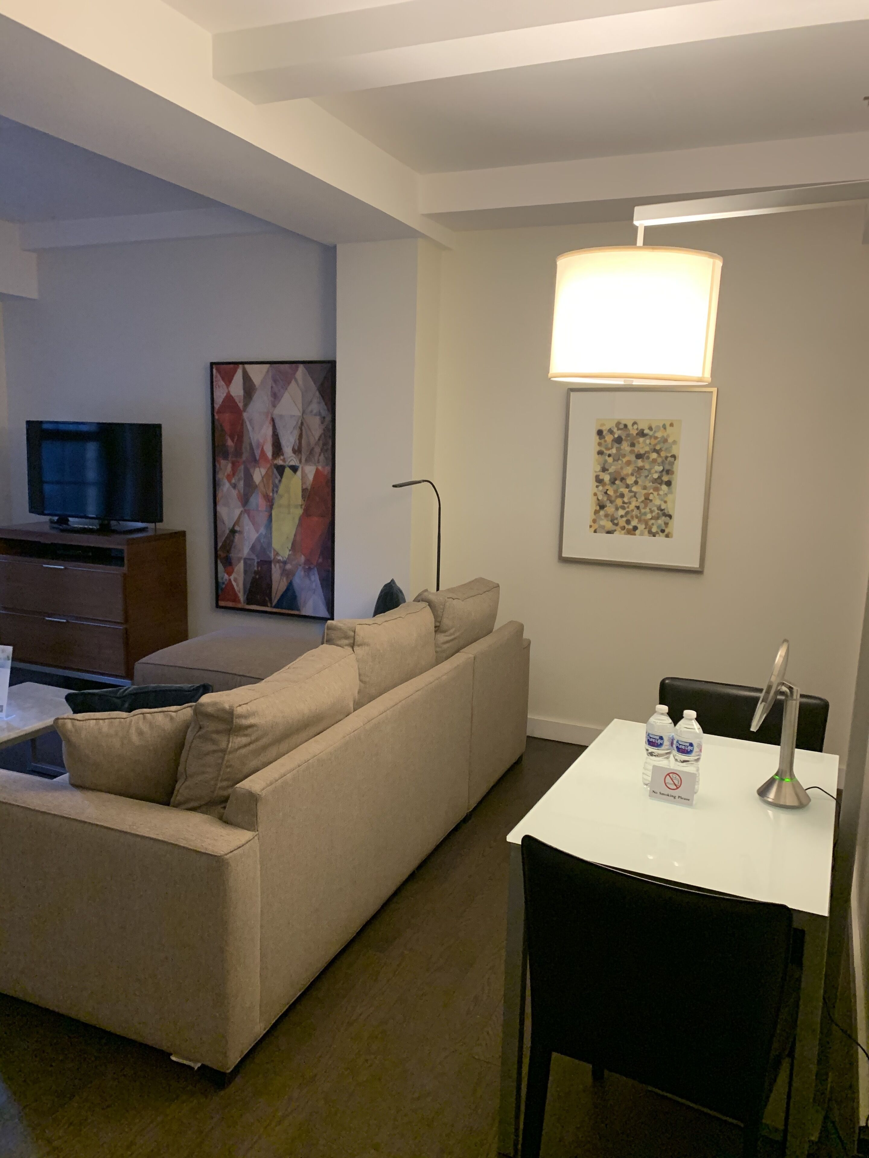 Una sala de estar moderna con sofá, televisor de pantalla plana, mesa de centro y zona de comedor con mesa y sillas.