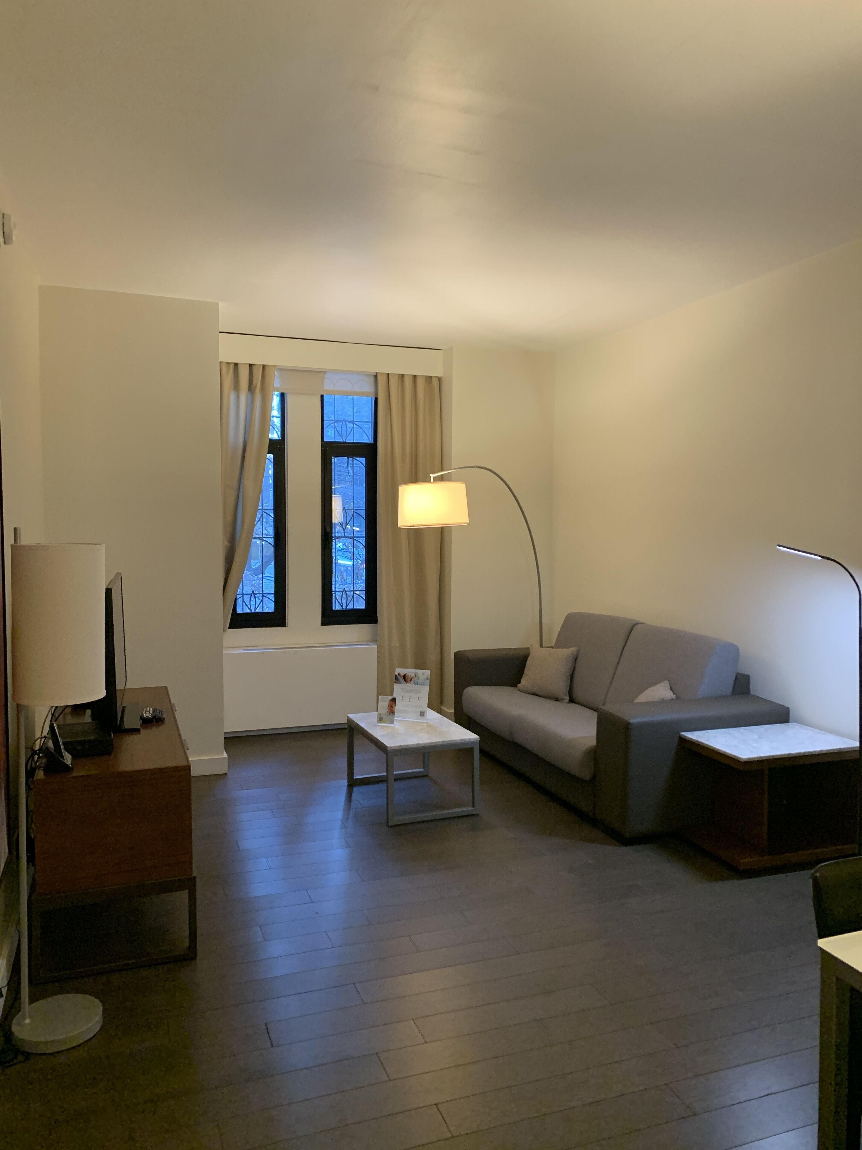A modern living room with a sofa, a coffee table, a lamp, and a television.