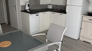 Cuina compacta amb armaris blancs, tauleig negre i rentaplats integrat.