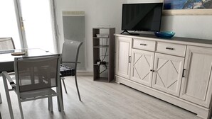 Un saló modern amb zona de menjador, un televisor sobre un moble i un quadre a la paret.