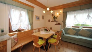 Una stanza accogliente con un tavolo da pranzo in legno, sedie imbottite verdi, un divano e una panca.