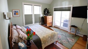 A bedroom with a bed, a dresser, a television, and a window with blinds. - A Village Bed and Breakfast (Newton)