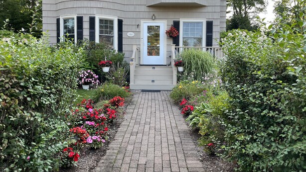 A two-story house with a brick pathway leading to a white door. - A Village Bed and Breakfast (Newton)