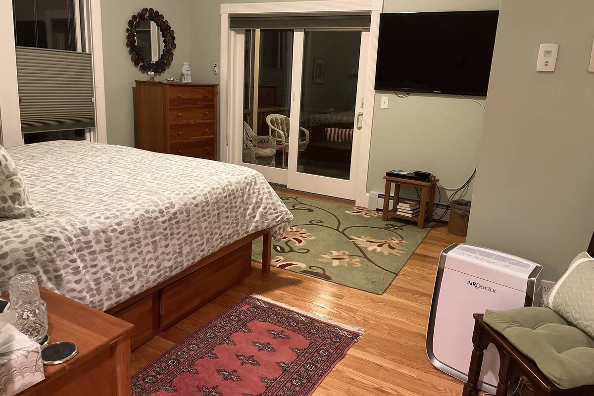 A bedroom with a bed, dresser, and an air purifier.