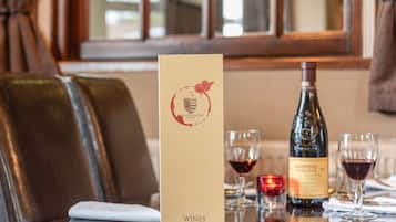 A restaurant table with a menu, wine bottle, and glasses.