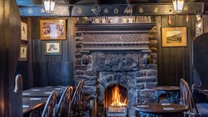 A cozy pub interior with a stone fireplace, wooden walls, and framed pictures. - The Fox and Hounds (Whitby)