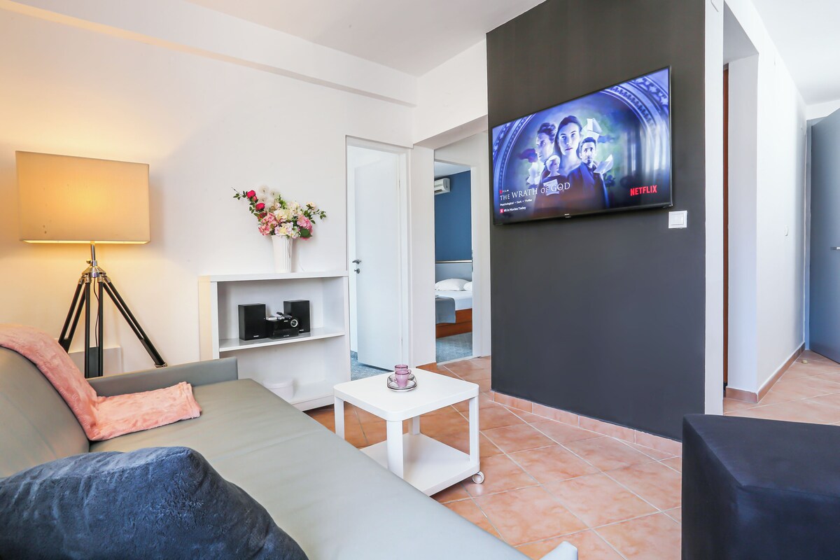 A modern living room with a flat-screen TV mounted on the wall, a sofa, a coffee table, and a lamp.