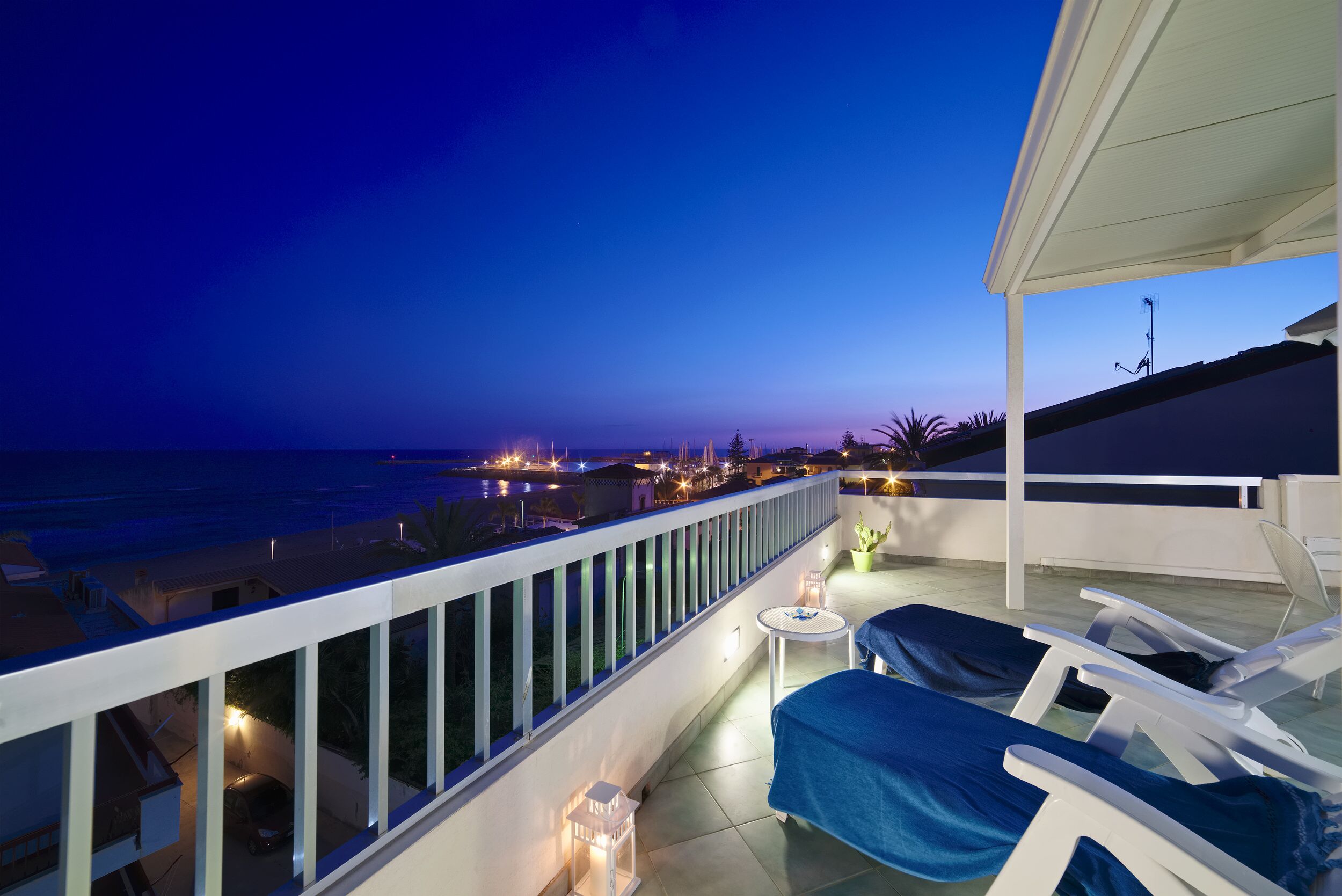 A balcony with two lounge chairs, a small table, and a potted plant.