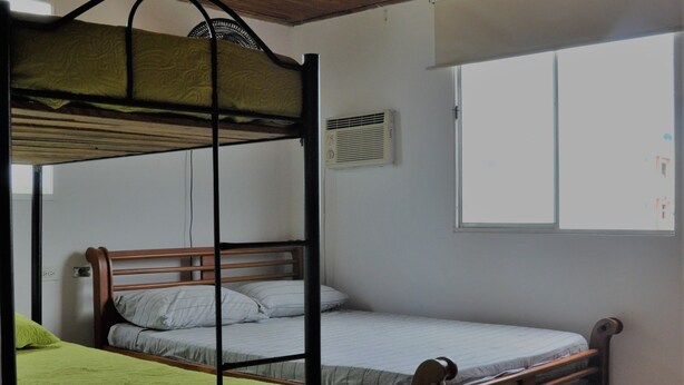 A room with a bunk bed, a single bed, a window, and a cabinet. - Sunset Terrace - Hostel (Cartagena)